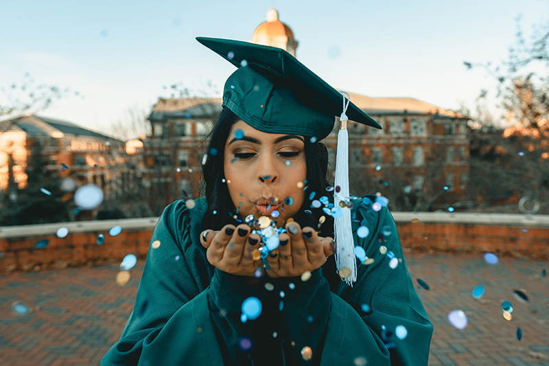 female graduate blowing confetti